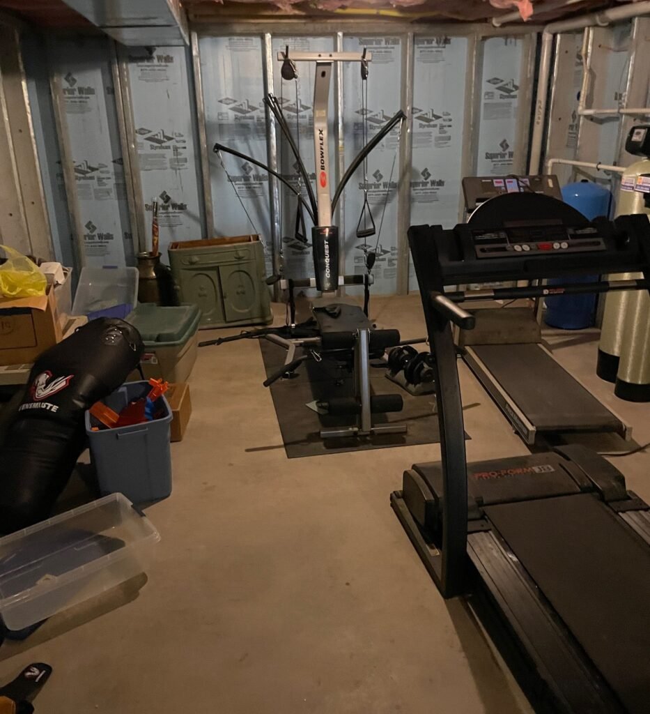basement cleanout in Wayne PA cluttered basement with exercise equipment and storage items before junk removal