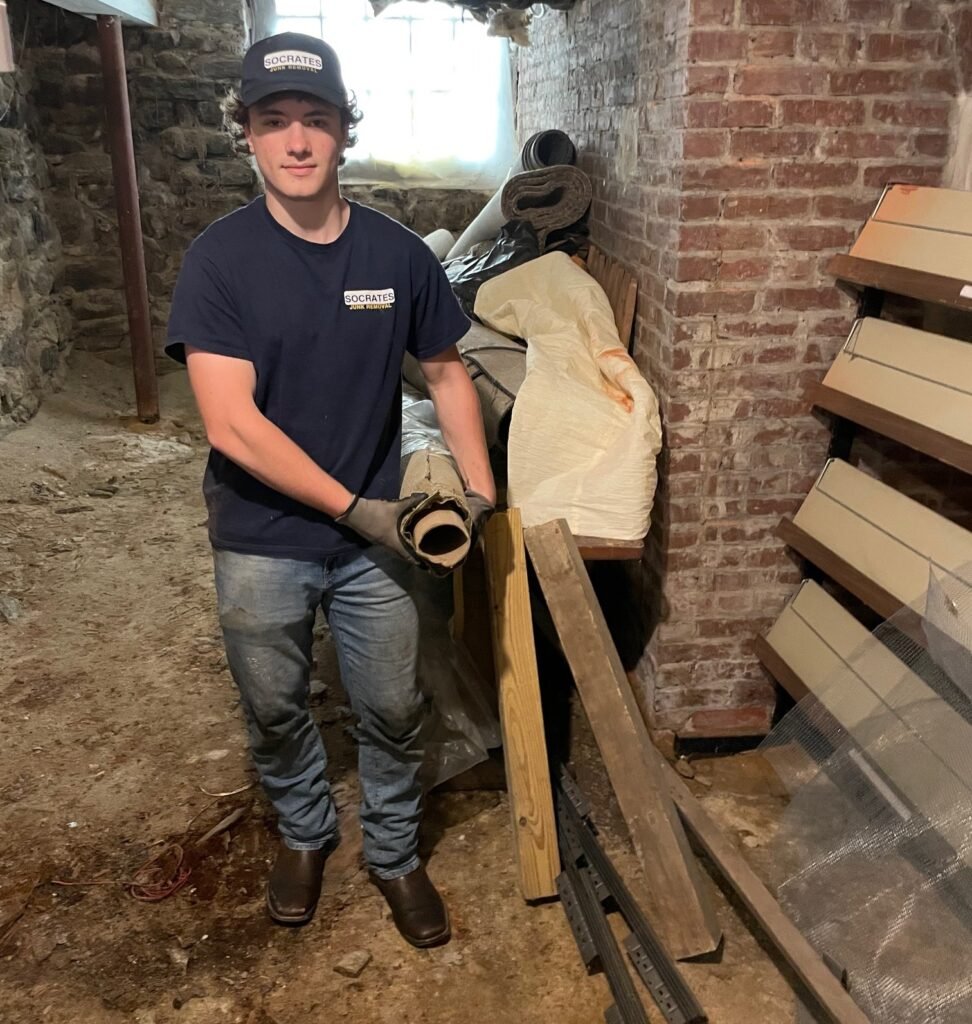 Socrates Junk Removal team member removing old carpet and padding during a basement cleanout in the Wayne area