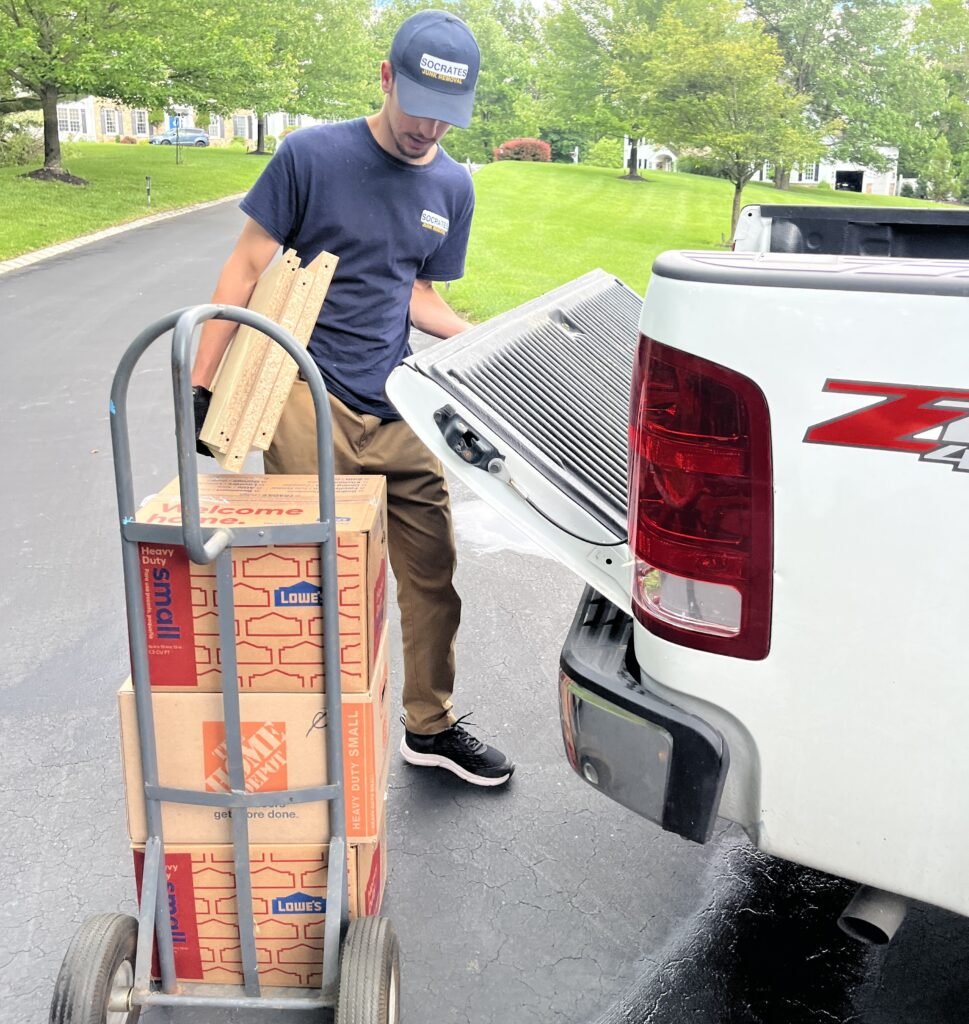 Socrates Junk Removal team member loading boxes into pickup truck during residential junk removal job in the Wayne area